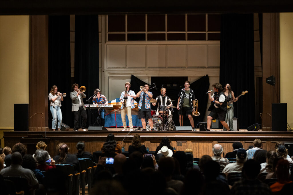 A band performs on a stage before an audience in an auditorium.