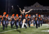 3 things to know about Mercer vs. The Citadel football game day: Oct. 31, 2026 A baton twirler leaps in front of a marching band on a football field at night.