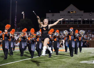 3 things to know about Mercer vs. The Citadel football game day: Oct. 31, 2026 A baton twirler leaps in front of a marching band on a football field at night.