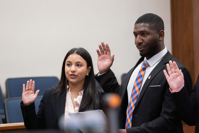 2026SwearingInMR-23 smaller A woman and a man in professional attire stand with their right hands raised to take an oath.