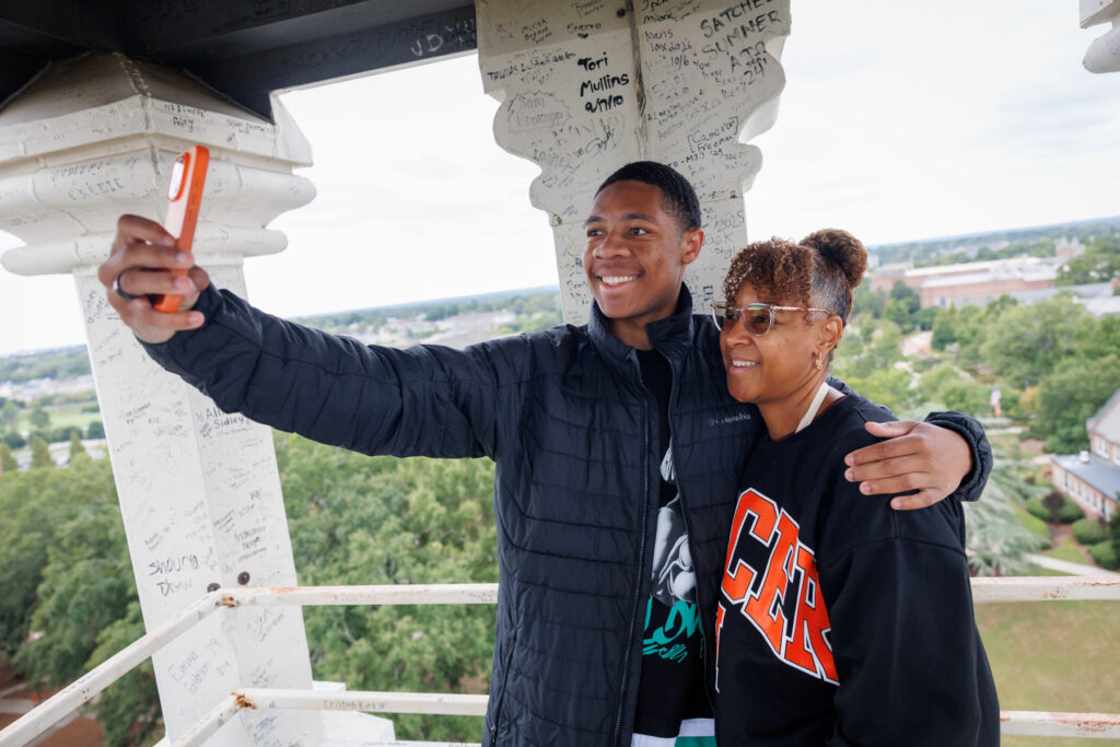 A Mercer student and his mom take a selfie together the tower of the Administration Building.