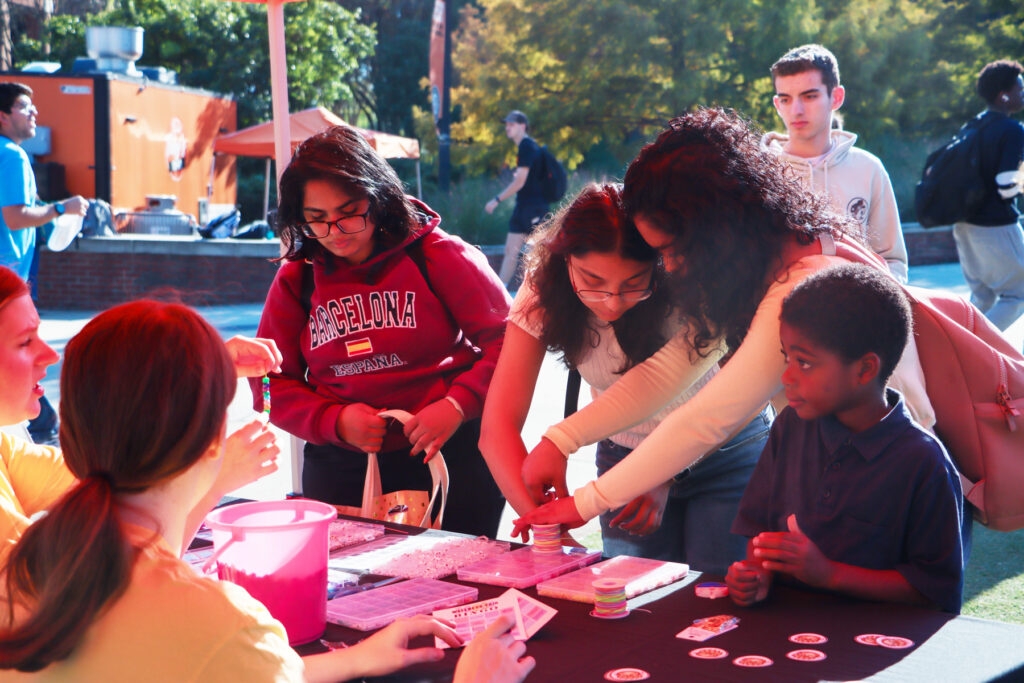 A group of people gathers around an outdoor table to make crafts.