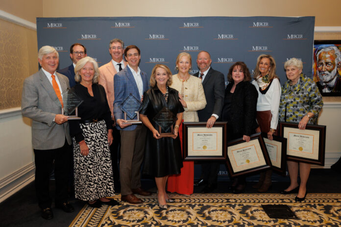 Group of ten people standing in front of a Mercer University backdrop, holding awards and certificates.
