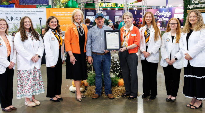 Georgia Agriculture Commissioner declares Mercer School of Medicine the State’s Official Georgia Grown Medical School Group of seven people posing for a photo, with one person holding a framed certificate at an agricultural trade show.