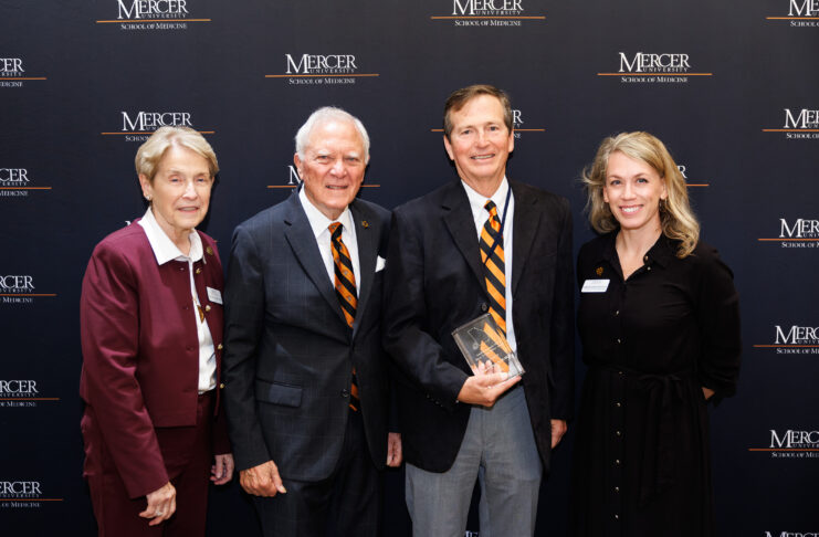 Mercer School of Medicine Dean Jean Sumner, M.D.; former Gov. Nathan Deal; Ed Grimsley, M.D.; and Mercer Vice President of External Relations Ember Bentley standing in front of a Mercer University School of Medicine backdrop.