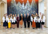 School of Medicine celebrates 2026 Nathan Deal Scholars A group of students and faculty members in professional attire posing for a photo in front of a stained glass mural.