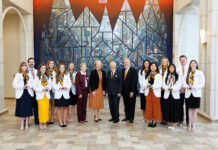 School of Medicine celebrates 2026 Nathan Deal Scholars A group of students and faculty members in professional attire posing for a photo in front of a stained glass mural.