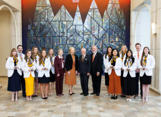 School of Medicine celebrates 2026 Nathan Deal Scholars A group of students and faculty members in professional attire posing for a photo in front of a stained glass mural.