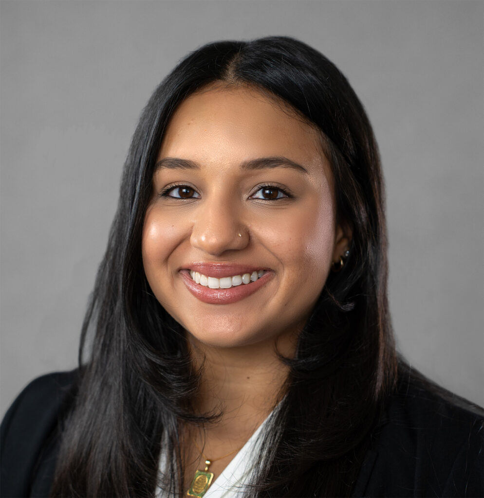 A professional headshot of a smiling woman with long dark hair.