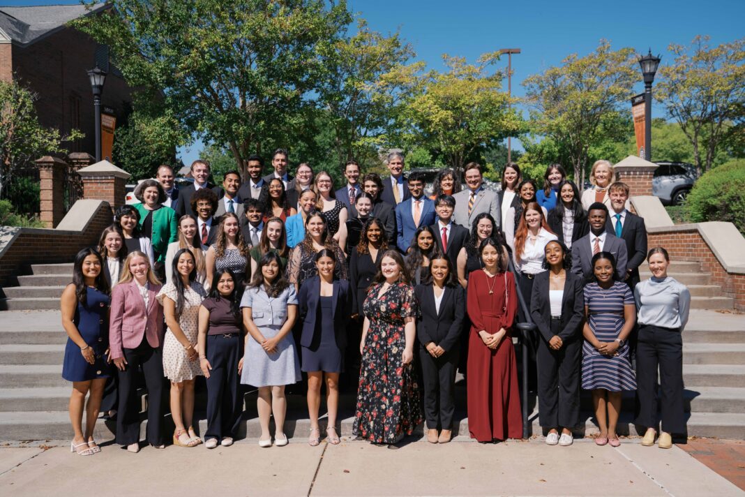 A large group of students in formal attire standing on outdoor stairs for a portrait.