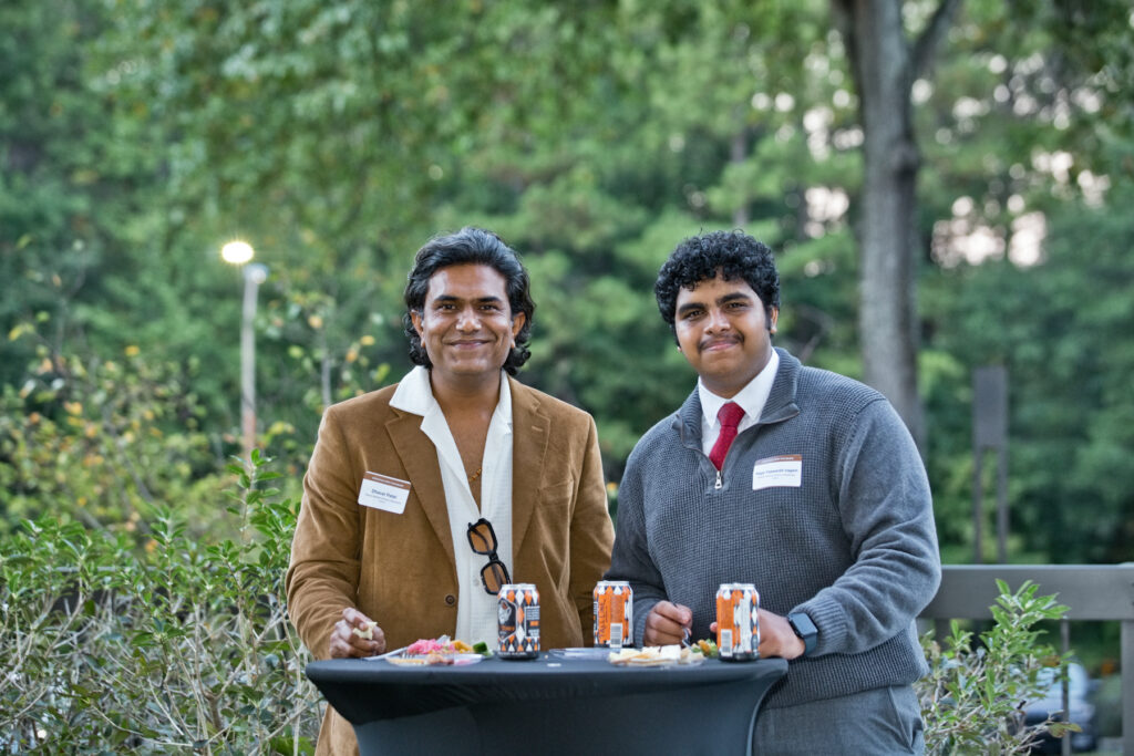 Two men standing at a high-top table outdoors.