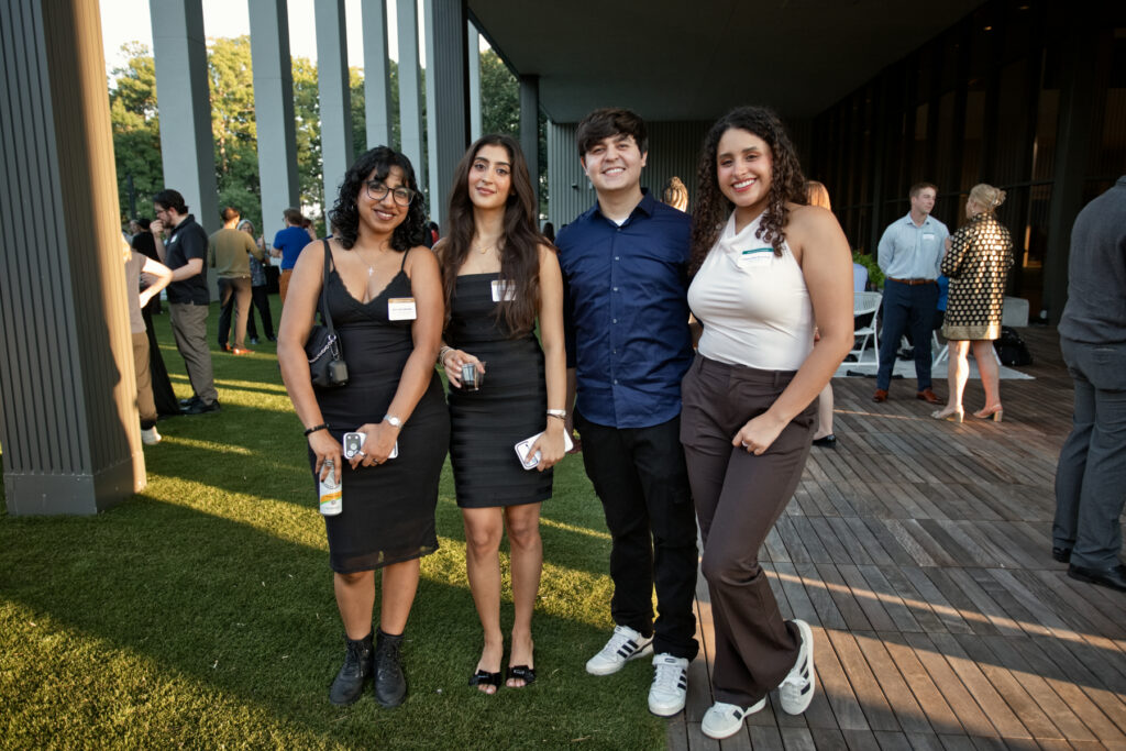 Four people stand together posing for a photo on an outdoor patio.