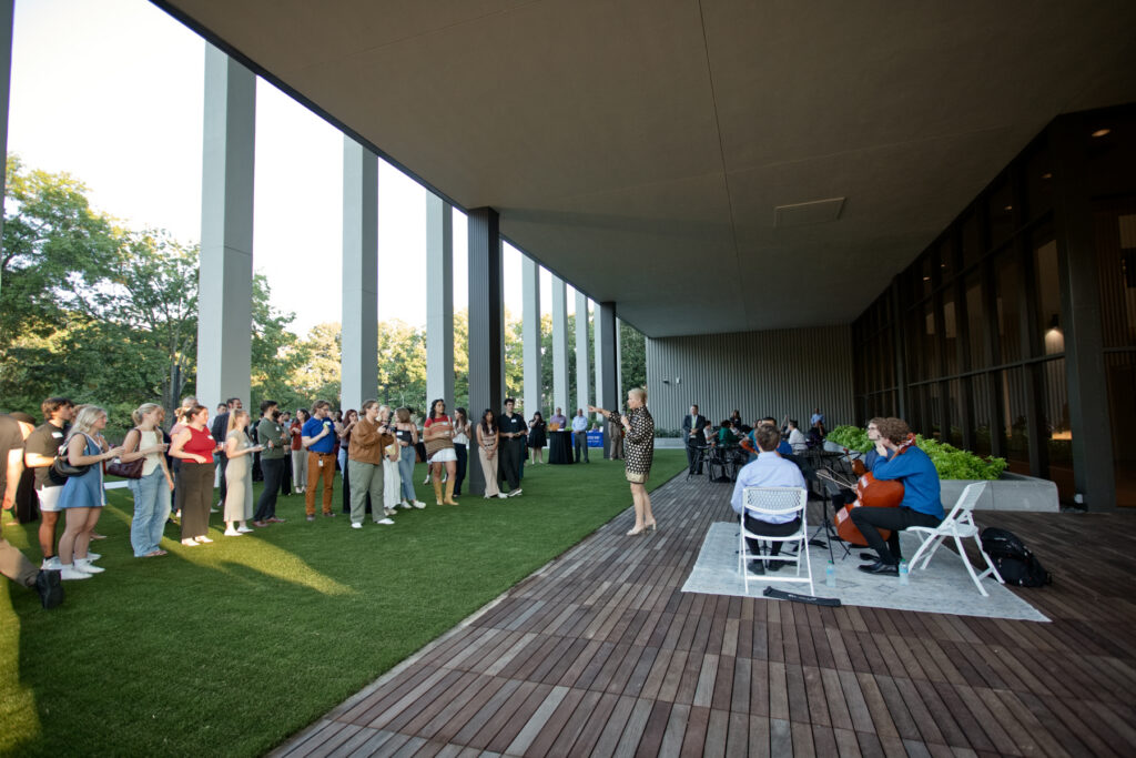 President Elkins speaks to a group of people standing on a lawn.