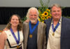 Mercerians honored with Cultural Arts Awards from Macon Arts Alliance Three people wearing blue ribbons with gold medals pose for a photo in front of a sunflower arrangement.