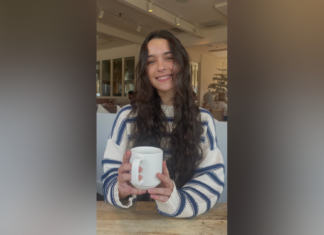 Junior selected for $5,000 Women in Transportation scholarship A woman with long wavy hair wearing a striped sweater smiles while holding a white mug at a cafe table.