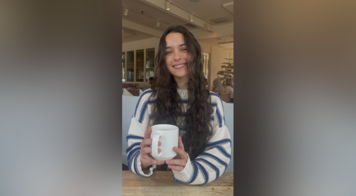 Junior selected for $5,000 Women in Transportation scholarship A woman with long wavy hair wearing a striped sweater smiles while holding a white mug at a cafe table.