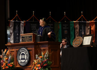 Penny L. Elkins, Ph.D., installed as 19th Mercer University president President Elkins in academic regalia speaks from a wooden podium at a university ceremony.